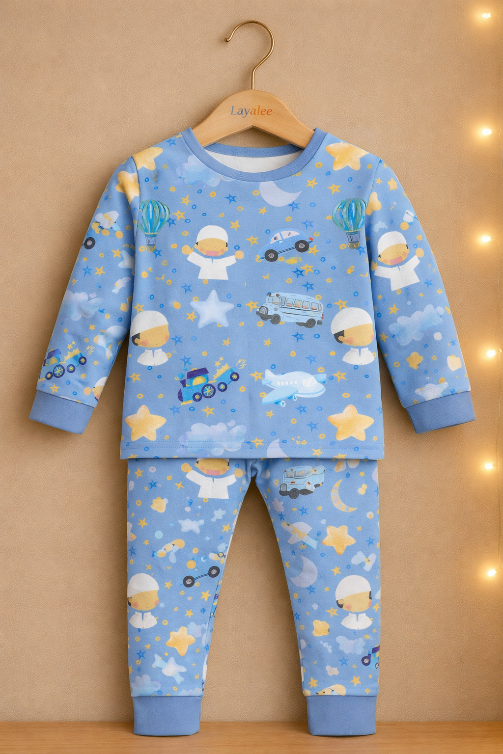 Children's pajama set with space-themed design on a hanger against a beige background.